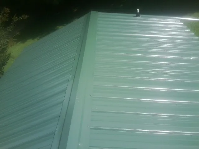New green metal panels meeting at the ridge of a roof — Flat Roof Repair work by our crew in Tennessee Ridge
