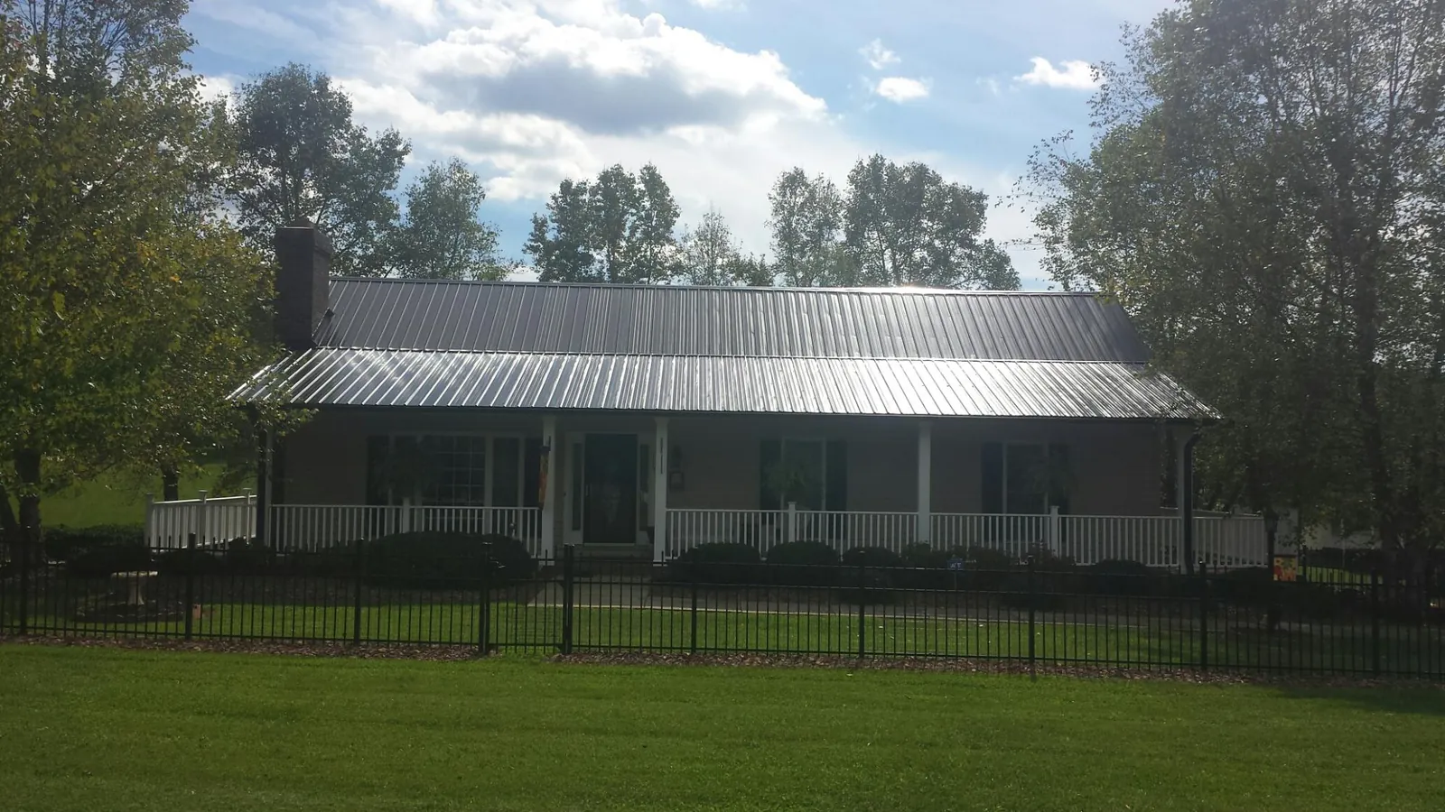 Gray metal roof on a brick ranch with a full width front porch — Gutter Guard Installation work by our crew in Tennessee Ridge