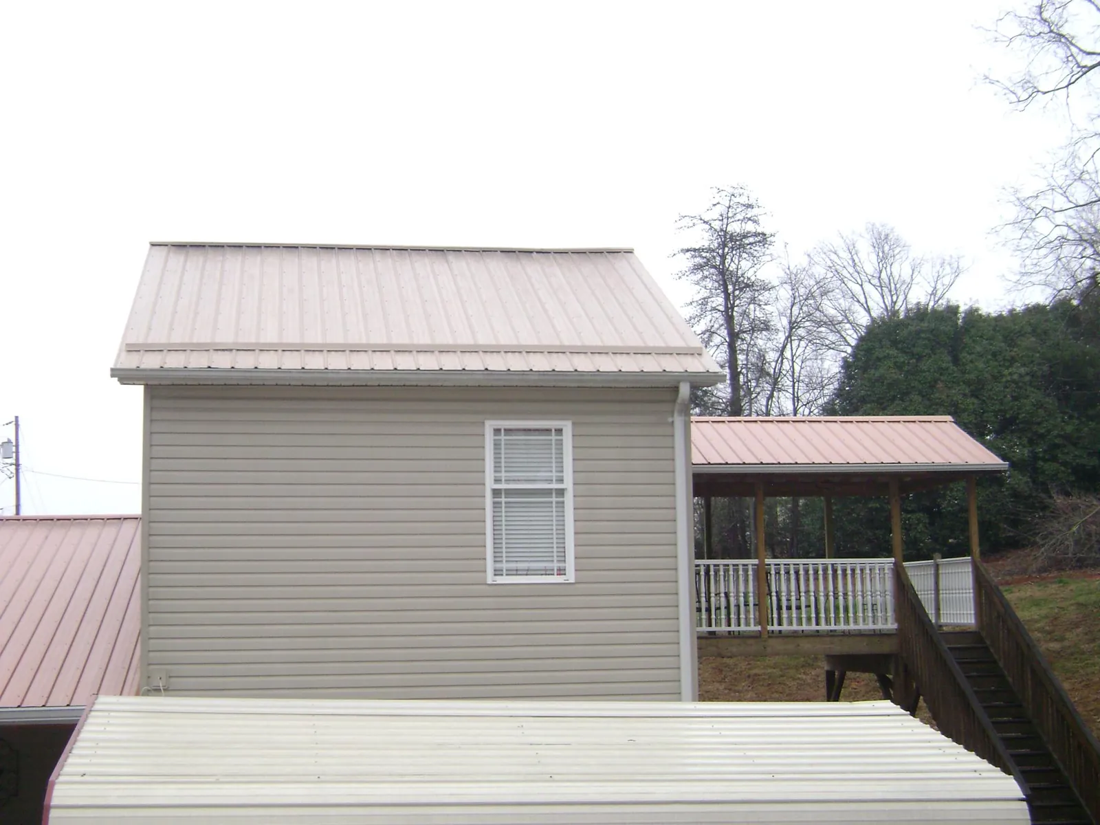Tan metal roofs on a two story addition and attached porch, from a Roof Replacement job in Tennessee Ridge