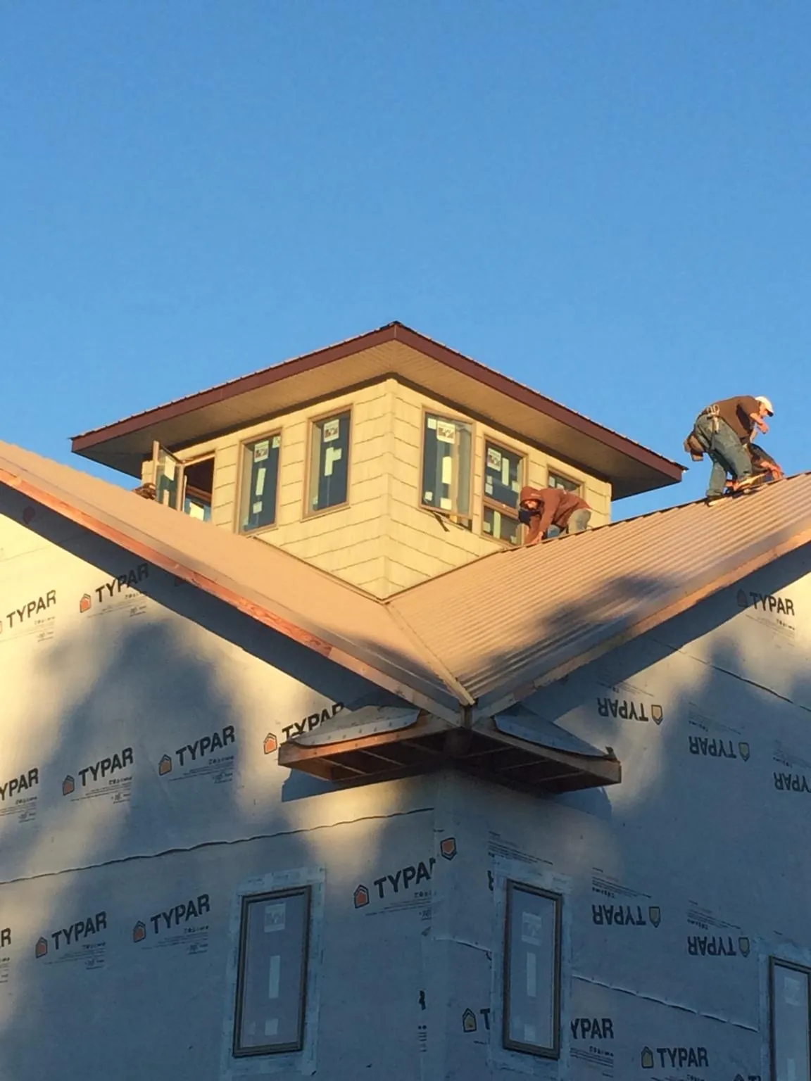 Roofers working around a rooftop cupola on a new metal roof at sunset — Roof Waterproofing in Tennessee Ridge by Roofing Brothers